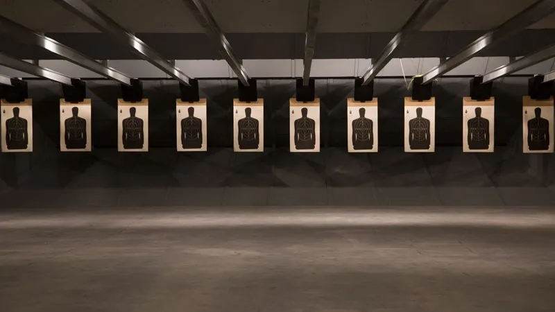 A controlled indoor shooting range displaying multiple silhouette targets for marksmanship training